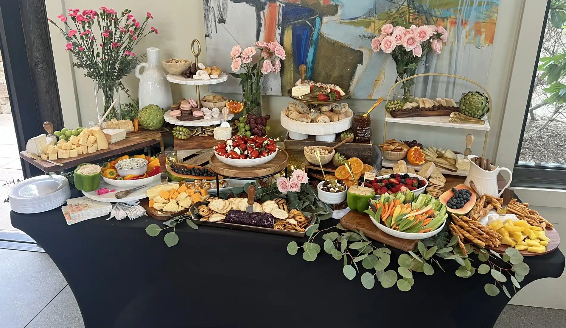 Multi-dimensional grazing table by Fork and Flare in Orange County featuring an abundant display of crudités, mixed berries, grapes, kiwi, blood oranges, caprese skewers, olive tapenade, hummus, spinach and artichoke dip, fresh bread, mixed nuts, and an array of cheeses including goat, brie, manchego, gouda, and cheddar, perfect for weddings, upscale parties, and corporate events.