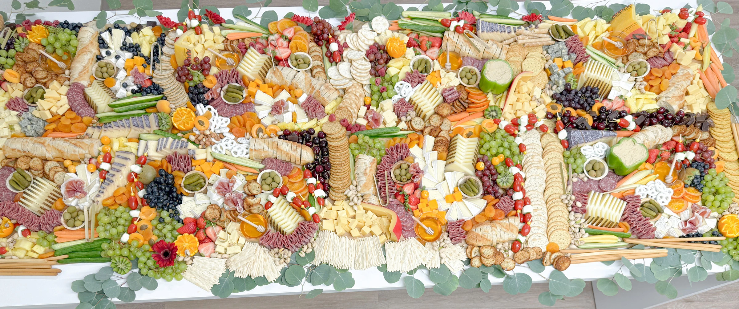 charcuterie grazing table in Orange County featuring brie, cured meats, cheeses, fruits, olives, crackers, and honeycomb, styled for weddings and events.
