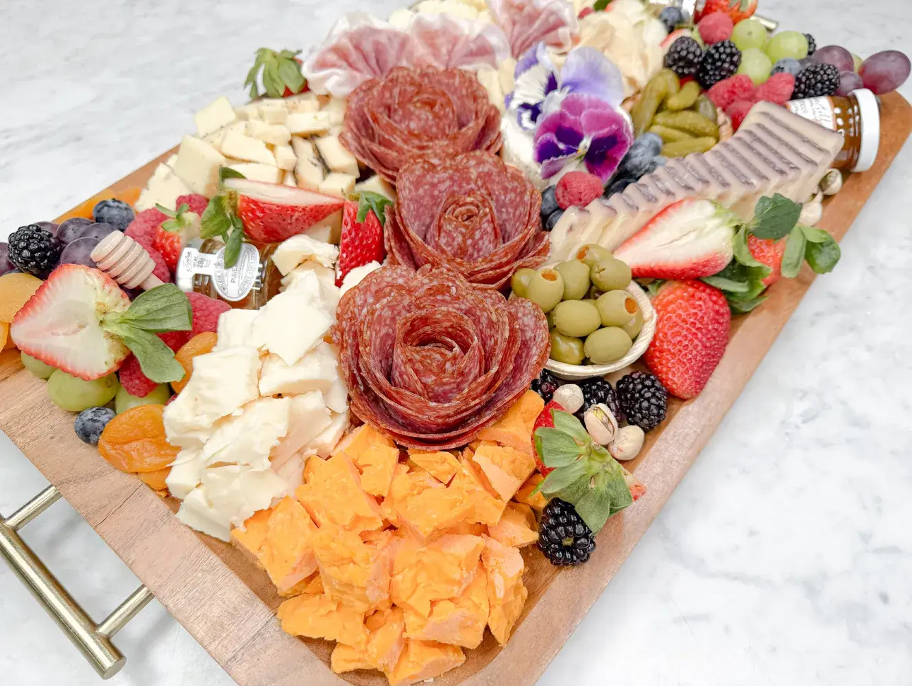 Fork and Flare charcuterie board in Newport Beach featuring fresh sliced salami and prosciutto, manchego, brie, gouda, wine cheese, espresso cheddar, red cheddar, Boursin garlic herb cheese, sheep and goat milk cheeses, Mediterranean olives, cornichons, mixed berries, grapes, honey drizzle, fruit jam, and stone ground mustard for Orange County delivery.