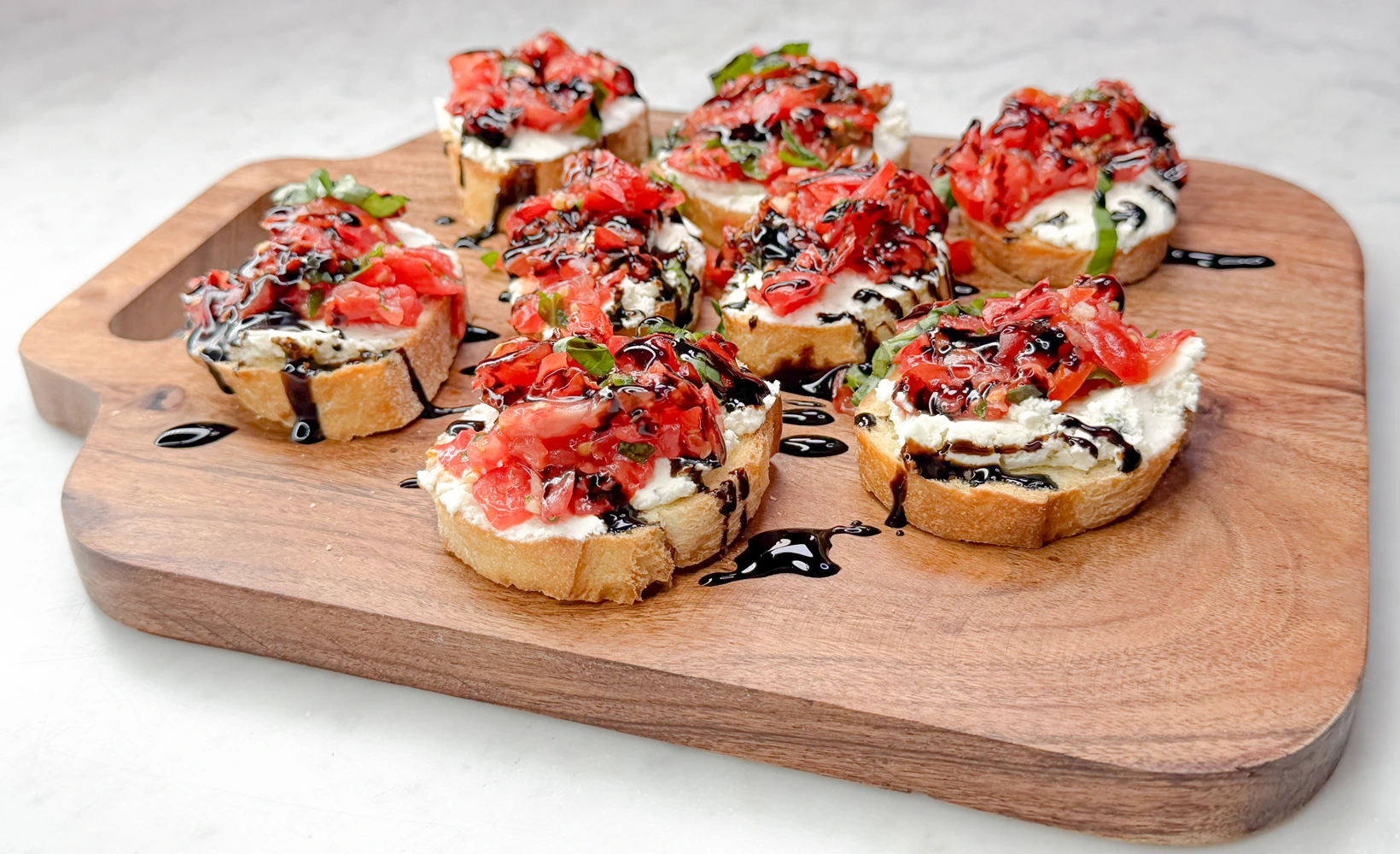 Best canapes in Orange County shown as bruschetta canapes by Fork and Flare featuring borsin cheese, olive oil brushed crostini, garlic, chopped basil, chopped tomato, and a balsamic glaze drizzle