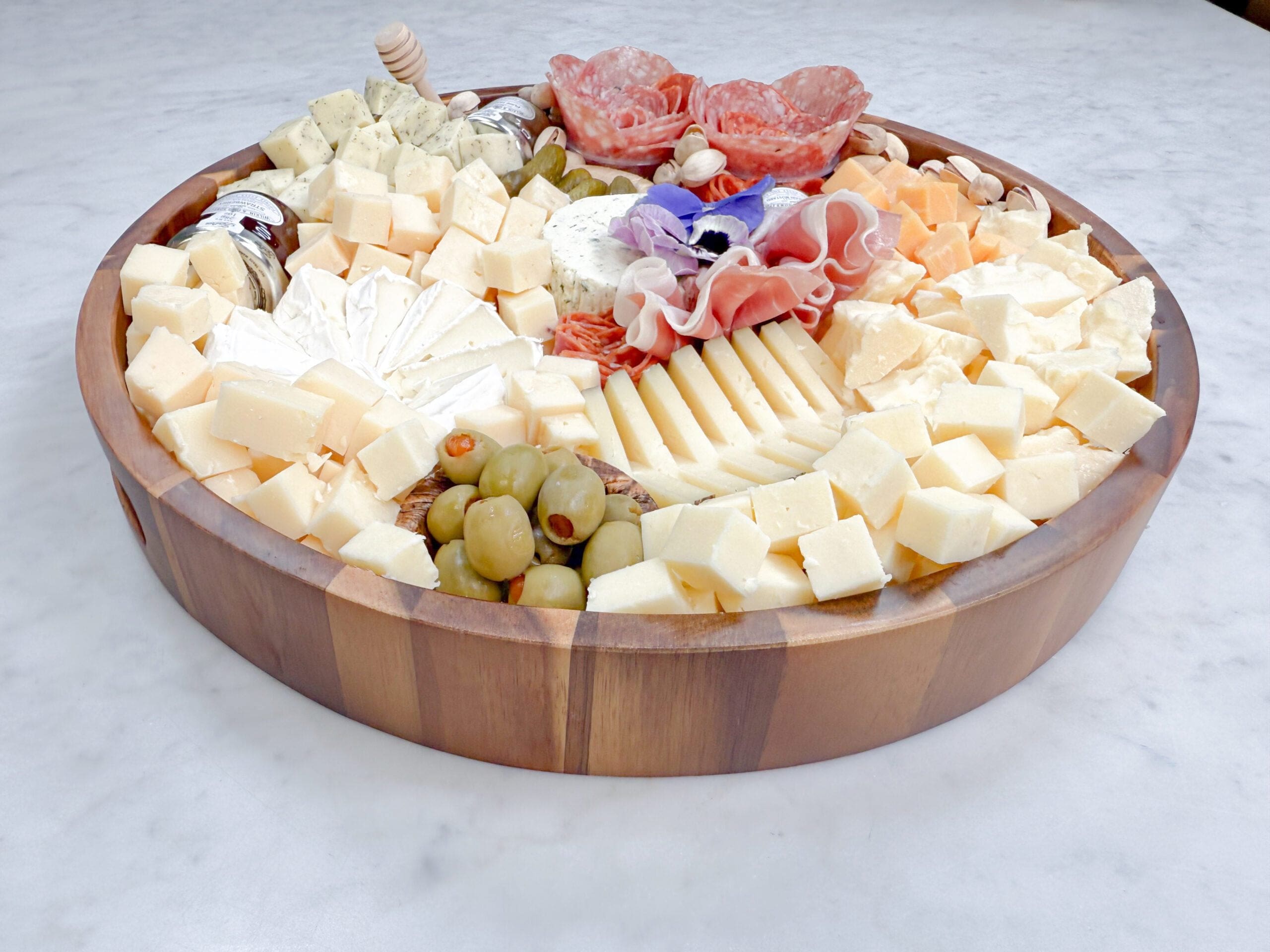 Best cheese board arranged on a wood serving board with artisan cheeses, hand-cut cured meats, fresh fruit, and elegant garnishes, showcasing a best-in-class gourmet charcuterie presentation by Fork and Flare.