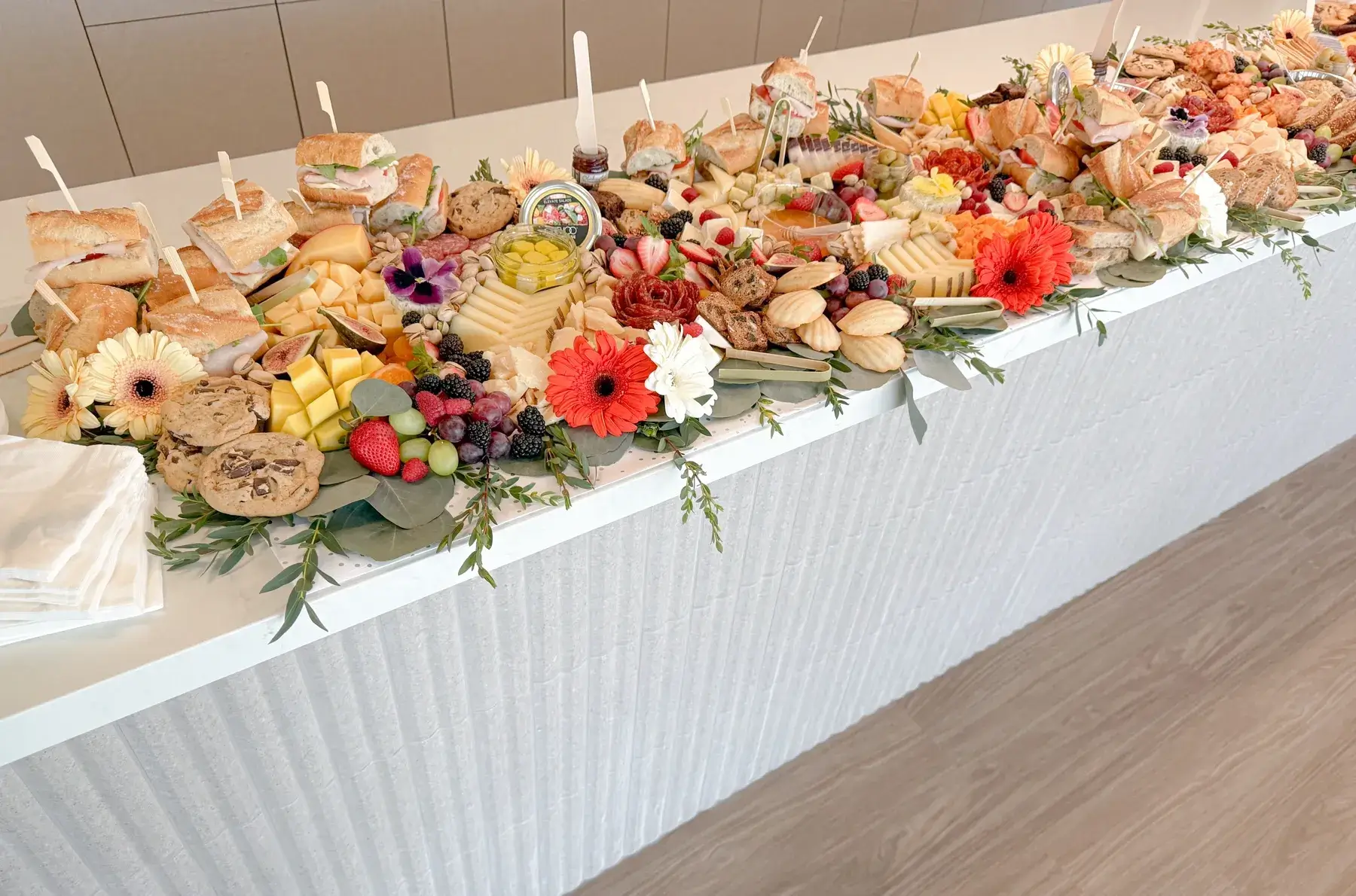 Fork and Flare charcuterie grazing table in Irvine California designed for 100 guests featuring a flat lay display of artisan cheeses, cured meats, fresh fruit, crackers, nuts, and gourmet accompaniments for catering events in Orange County.