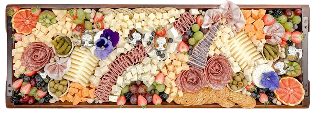 Assorted charcuterie board with cheeses, meats, fruits, olives, and crackers on a metal tray.